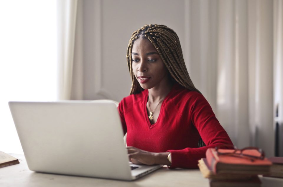 A woman in a red sweater working on a laptop